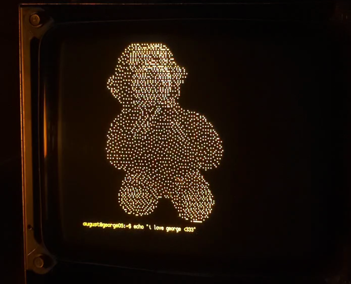 A stuffed monkey with the words 'echo i love george' written underneath, displayed on an amber crt monitor